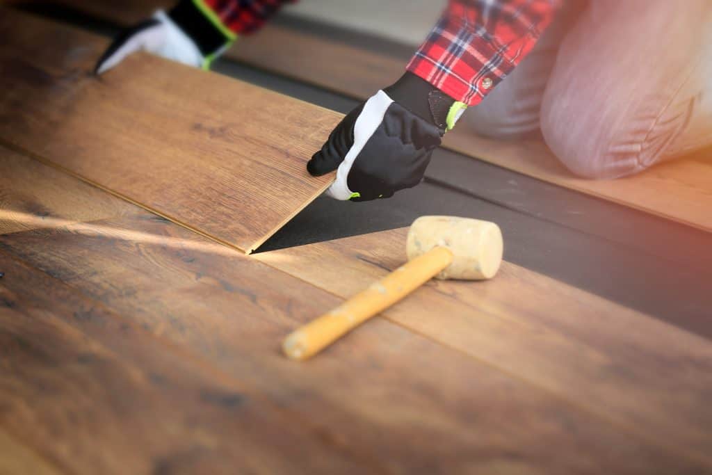 Man installing floor boards with rubber mallet